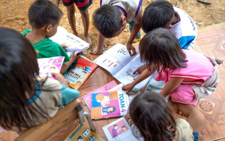 Group of children reading and studying together outdoors.