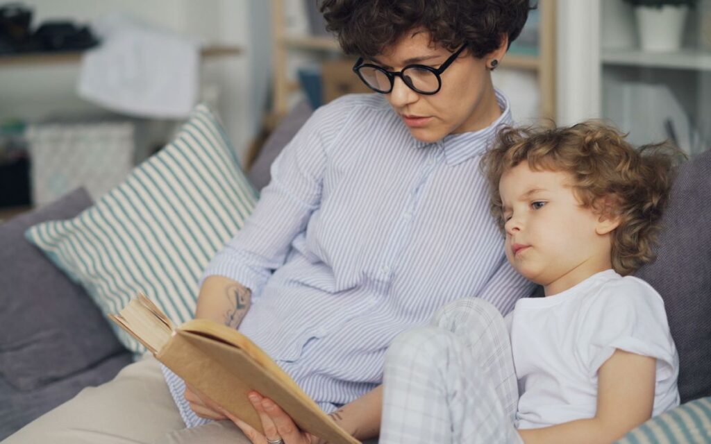 A mother and child reading a book together, sharing a cozy moment indoors.
