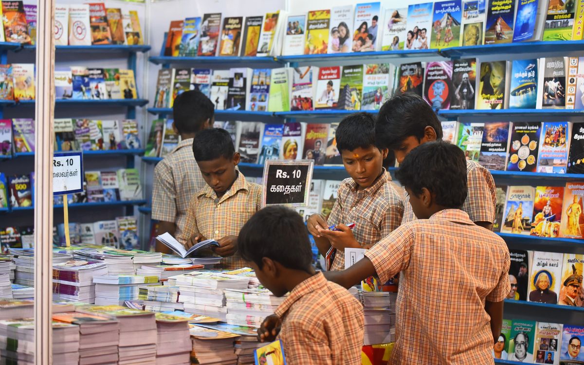 Children engaged in browsing books at a stall in Madurai, highlighting interest in reading and education.
