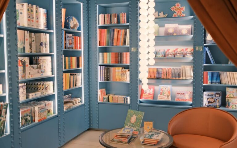A bright children's bookstore featuring blue shelves filled with colorful books.