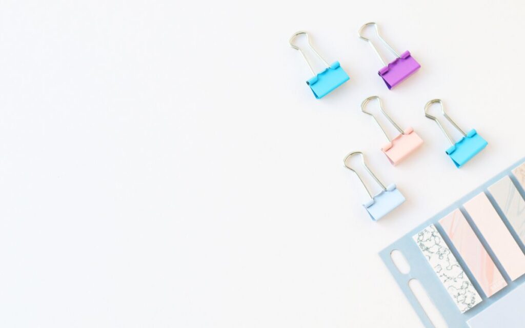 Vibrant stationery clips and paper strips on a white background with space for text.