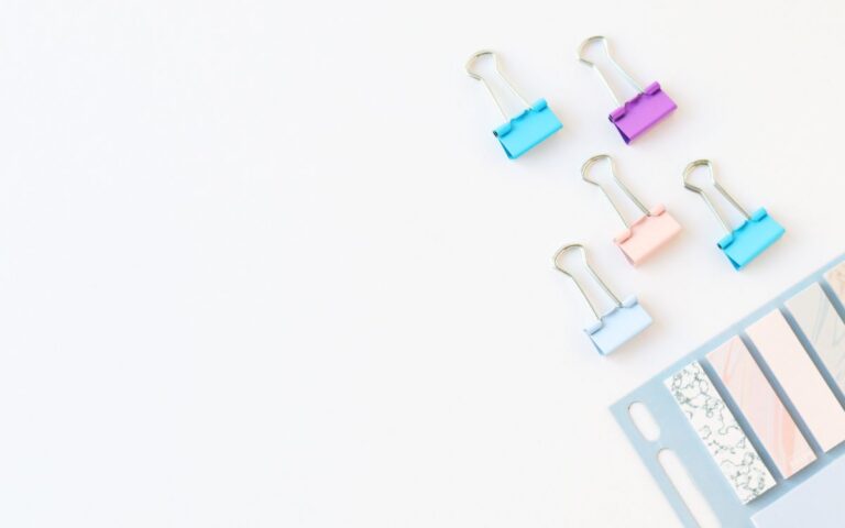Vibrant stationery clips and paper strips on a white background with space for text.