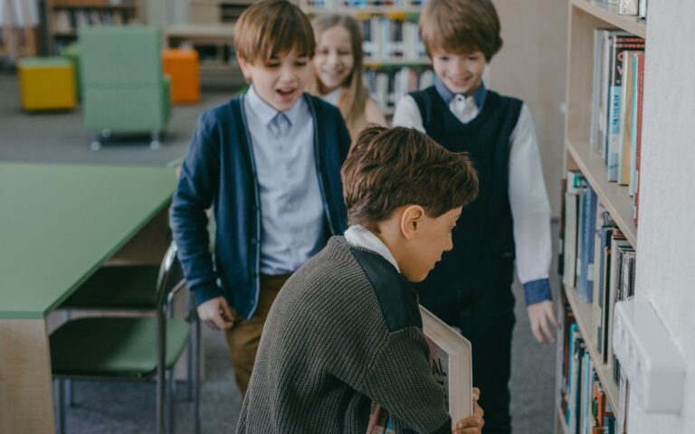 Group of children interacting by bookshelves in a school library environment.