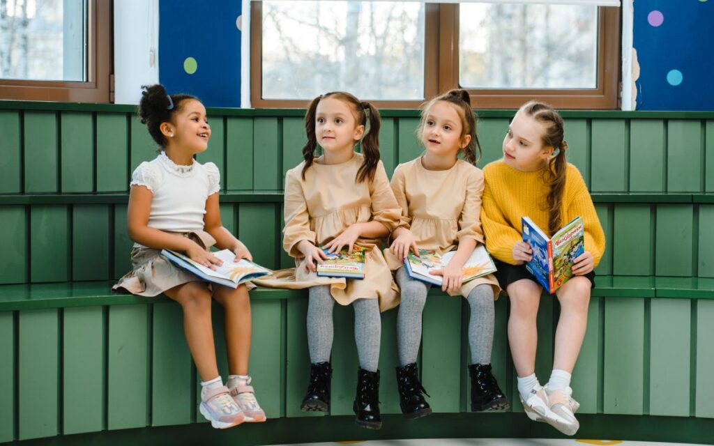 Four girls sitting indoors reading books, fostering a love for learning and education.