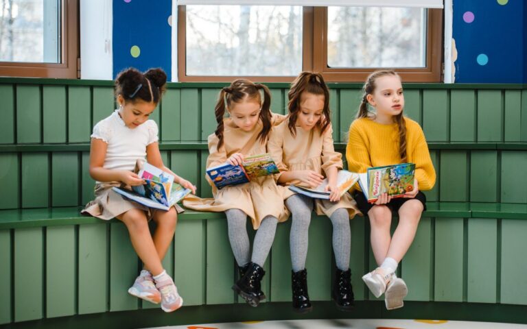 Group of young girls sitting indoors, reading and studying in a classroom setting.