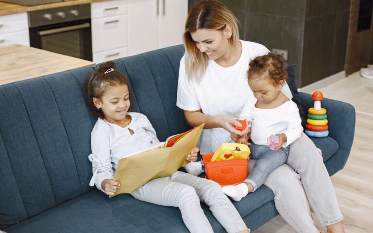 A mother reading with her daughters on a sofa, enjoying family time indoors.