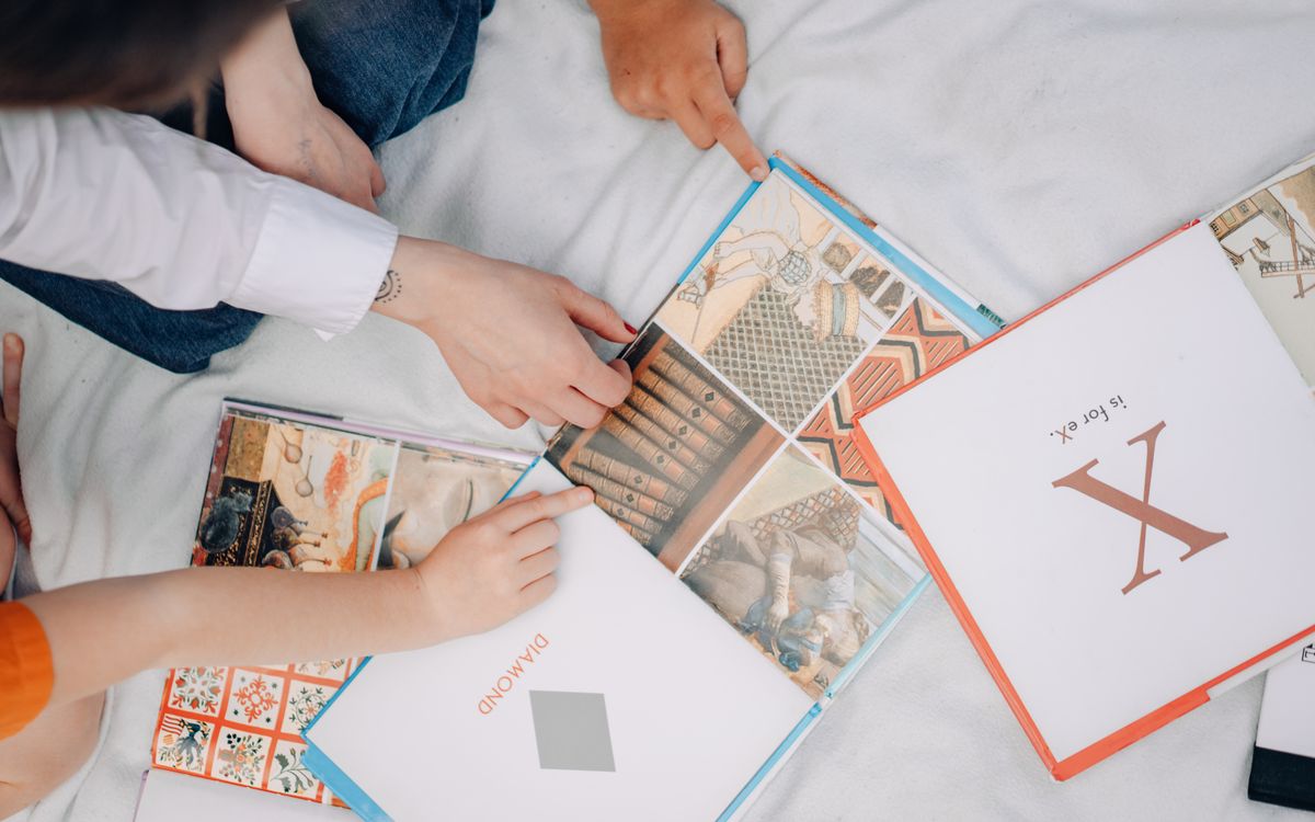 Top view of children exploring colorful illustrated books, fostering learning and interaction.