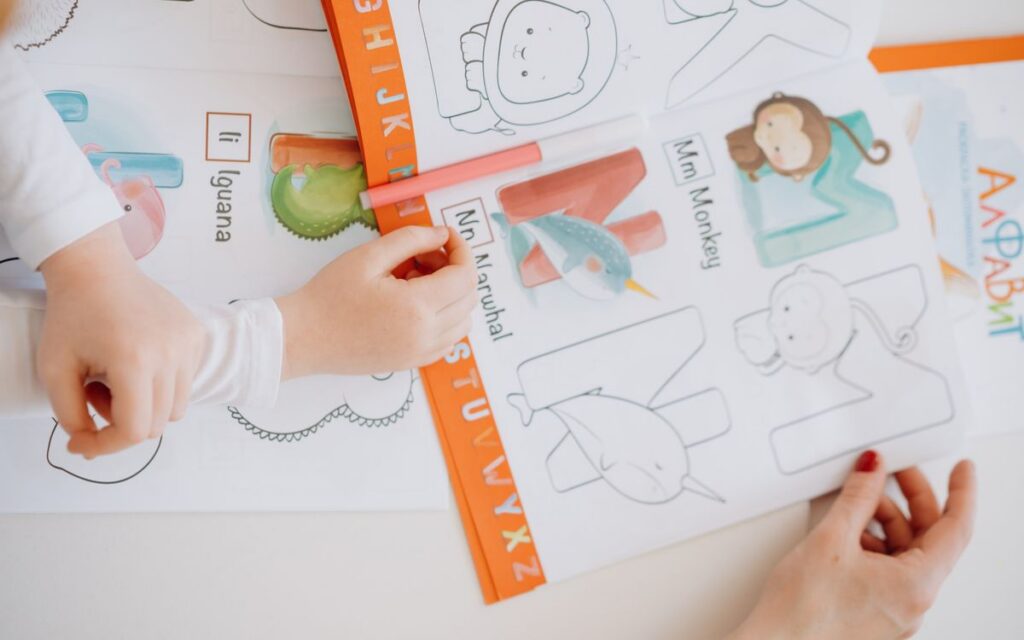 Children engage in learning the alphabet using a coloring book with bright illustrations.