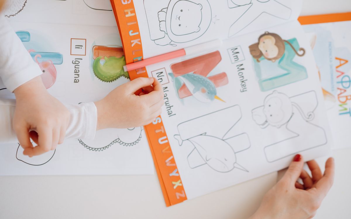 Children engage in learning the alphabet using a coloring book with bright illustrations.