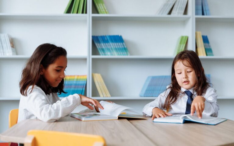 Two young girls enjoying books in a vibrant school library setting.
