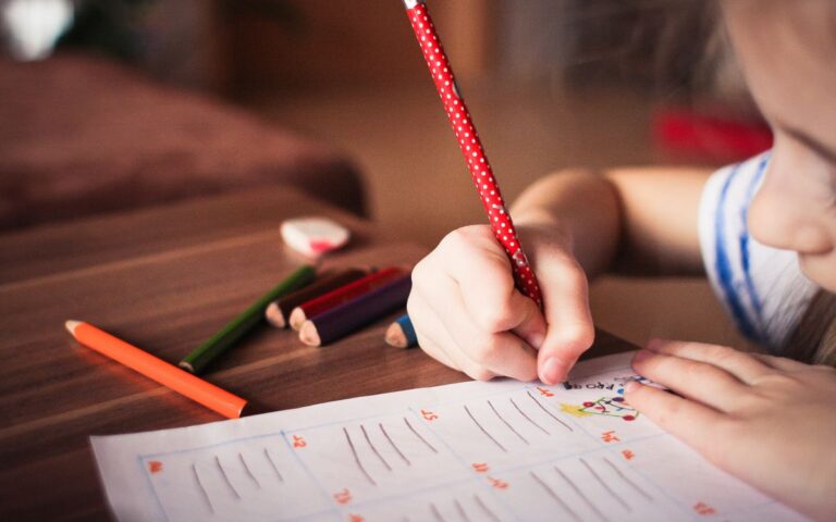 Close-up of a child completing homework using colorful pencils, focused on learning.