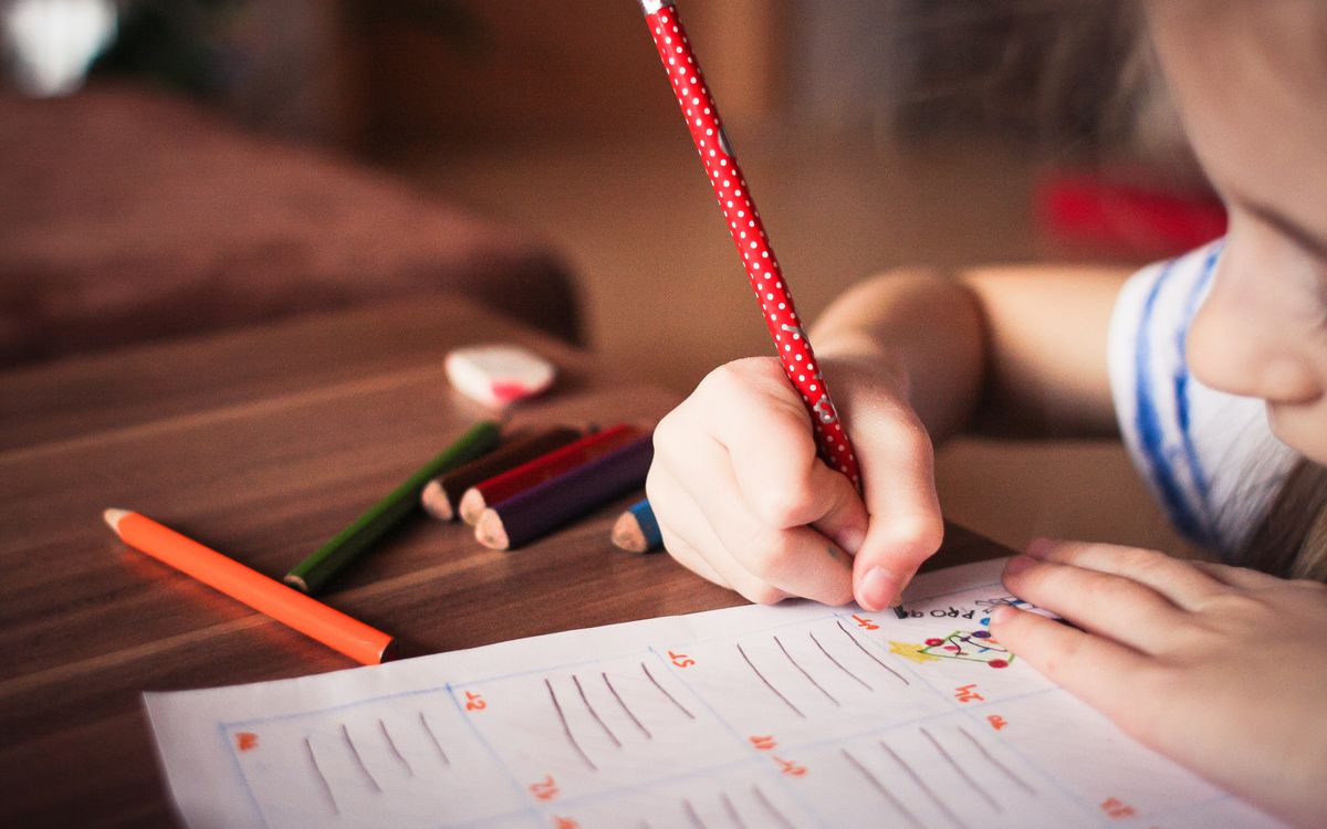 Close-up of a child completing homework using colorful pencils, focused on learning.