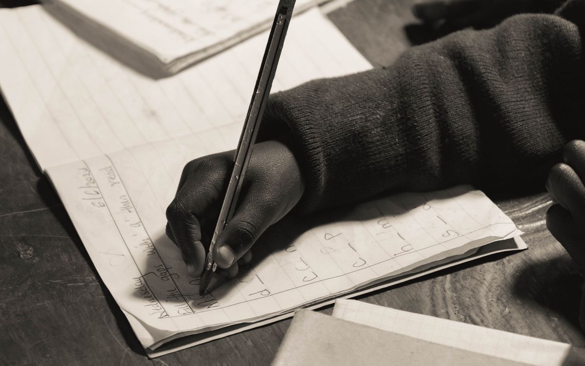 Close-up of a child writing in a notebook, focusing on handwriting practice.