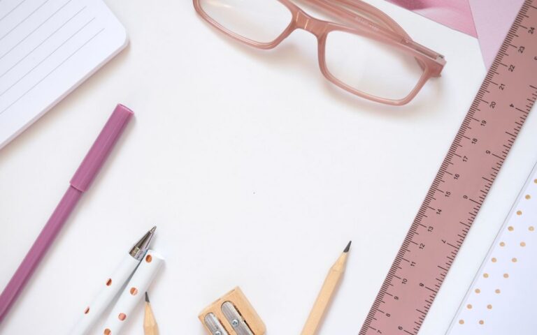 A neatly arranged flat lay of office supplies including pink glasses, ideal for creative projects.