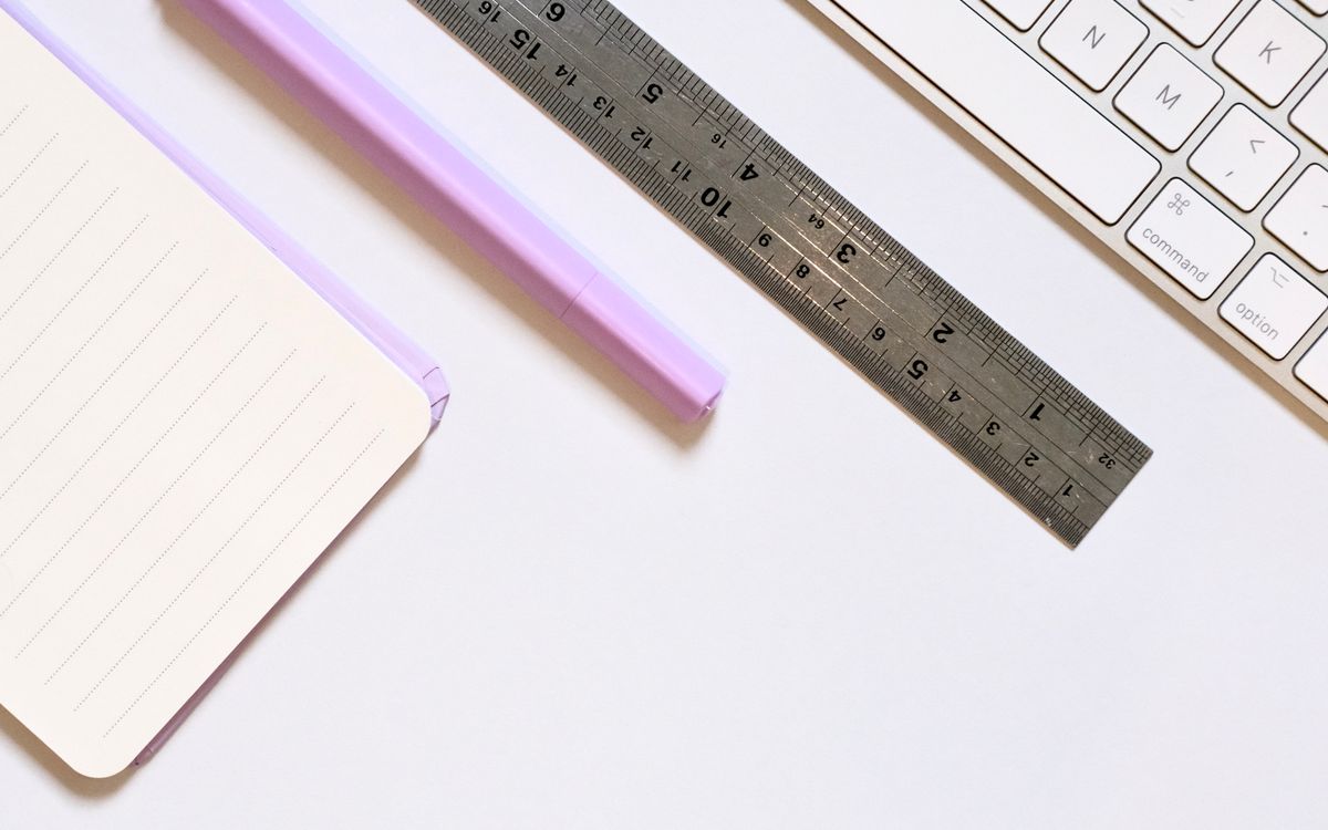 A clean desk setup with a notebook, pen, ruler, and keyboard for productivity and organization.