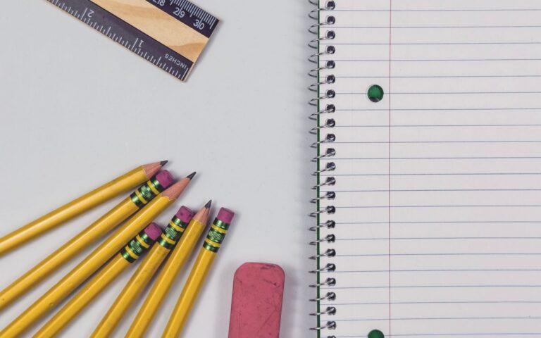 A neat arrangement of yellow pencils, eraser, ruler, and spiral notebook on a flat surface, perfect for educational them