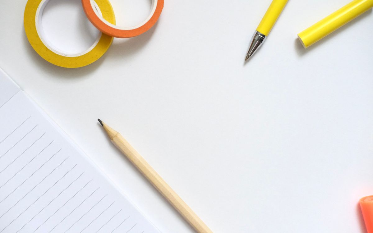 Flat lay of colorful stationery tools including a notebook, pencil, and pens for creative work.
