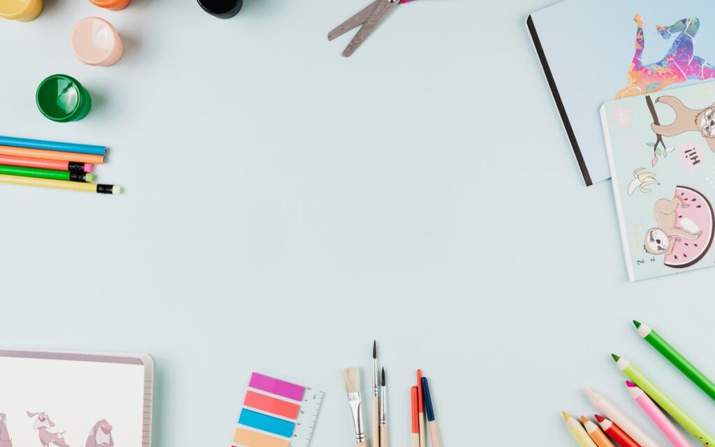 Top-view flat lay of art supplies on a pastel surface with ample copy space.