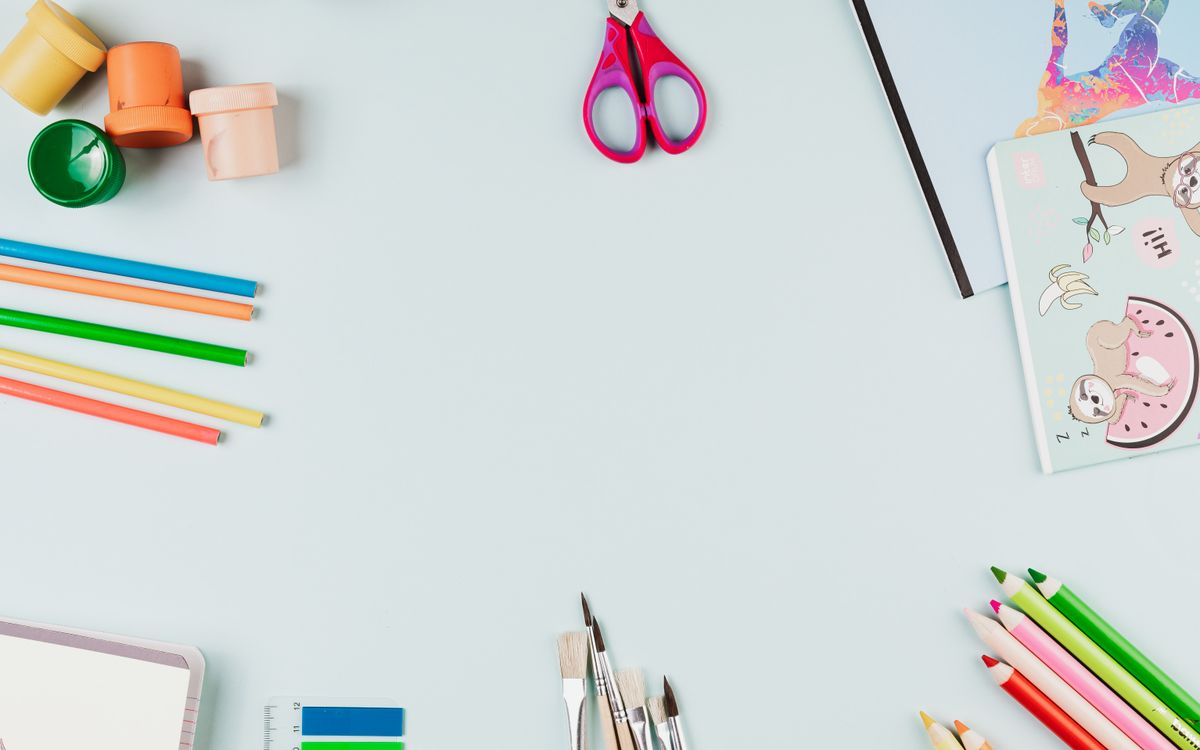 A creative flat lay of colorful art supplies arranged on a light blue background with copy space.