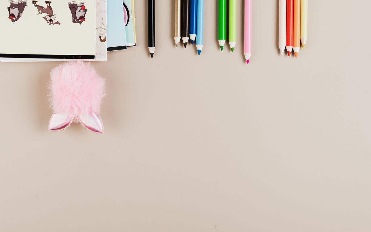 Top view of vibrant color pencils and cute accessories on a beige background, perfect for creative projects.