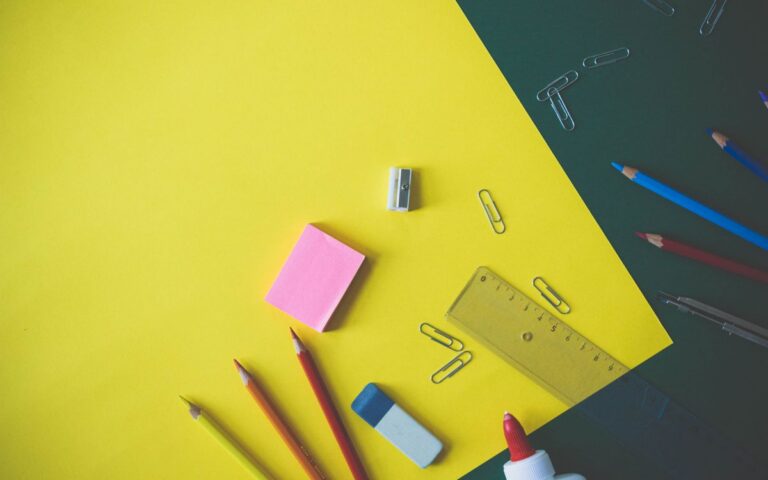 Flat lay of colorful school supplies arranged on a vibrant yellow background, ideal for back-to-school themes.