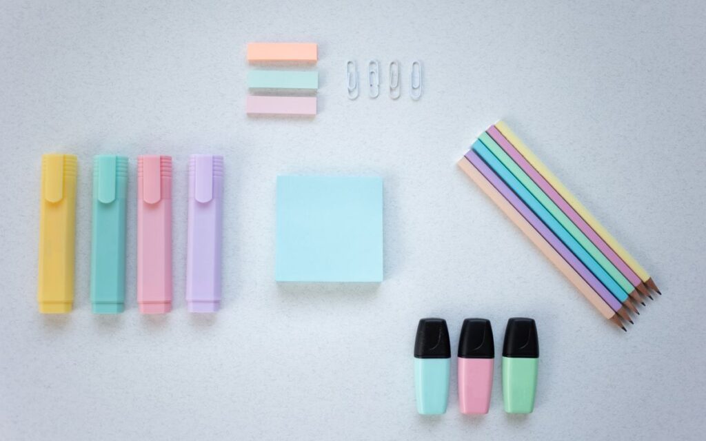 A vibrant collection of stationery items arranged flat on a white surface.