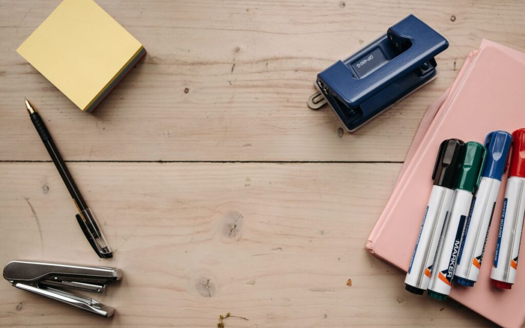 Flat lay of office supplies on a wooden desk for a neat workspace setup.