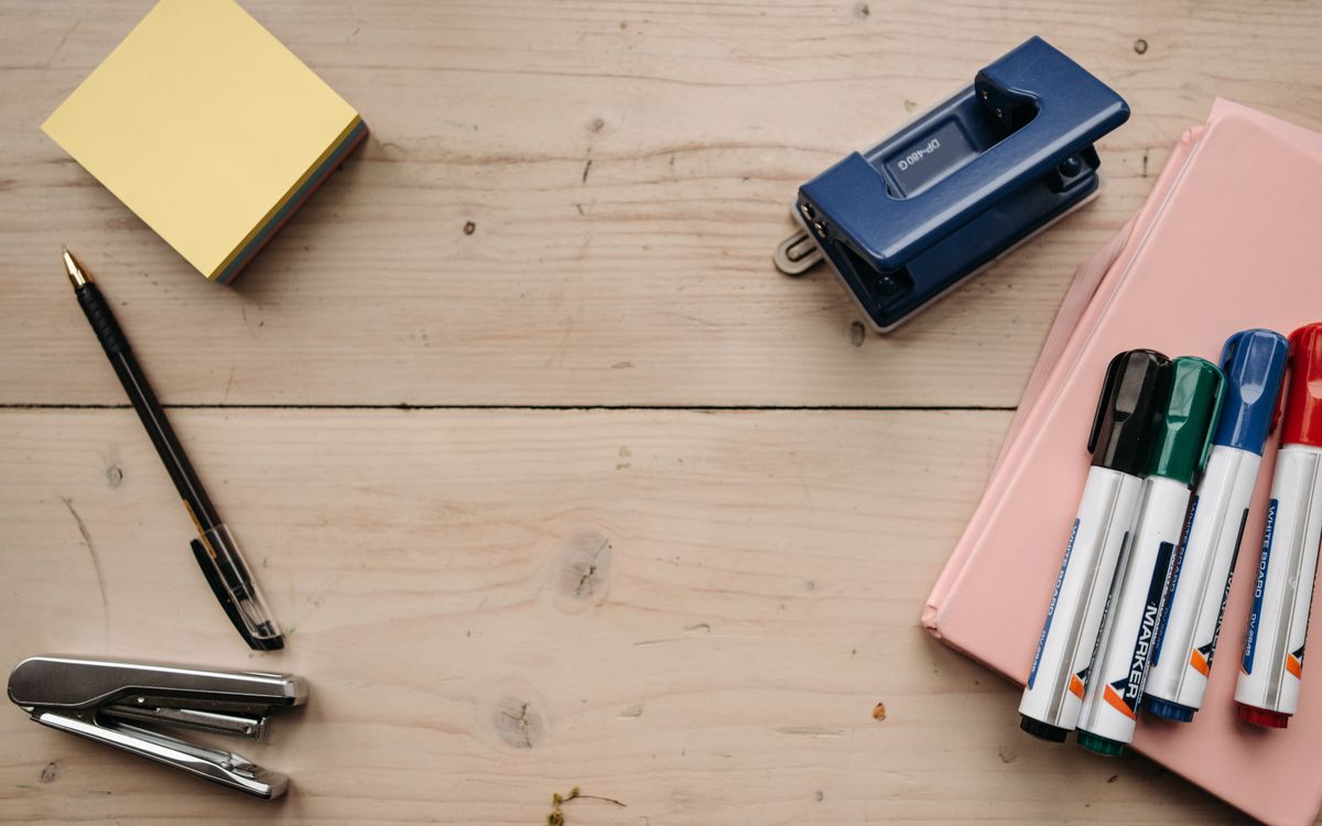 Flat lay of office supplies on a wooden desk for a neat workspace setup.