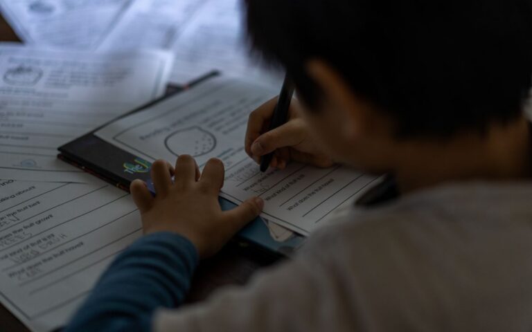 Young child focused on writing homework indoors. Educational and learning concept.