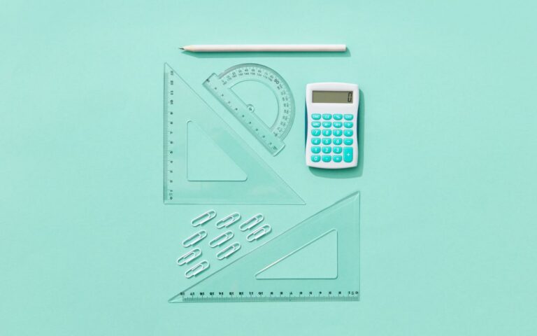 Flat lay of school supplies including calculator, rulers, and pencil on pastel background.