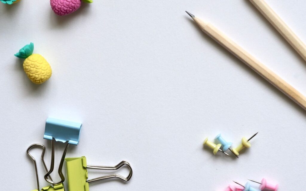 Flat lay of vibrant stationery on a clean white background for a creative work environment.