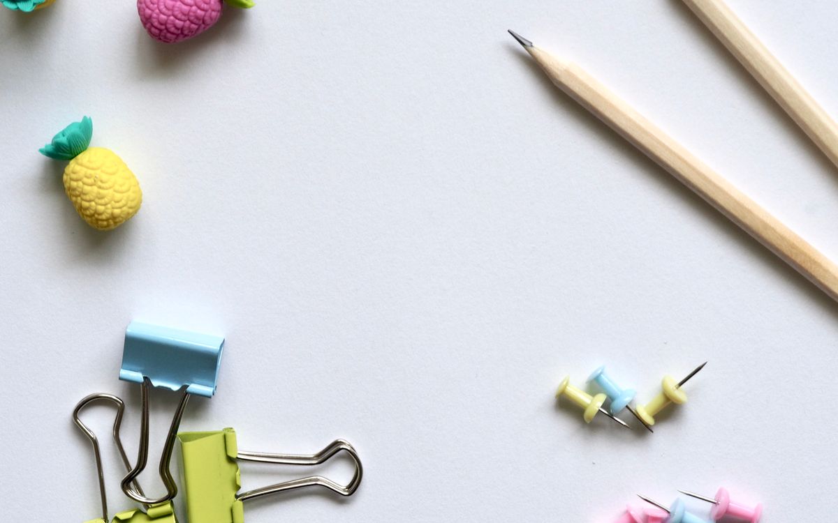 Flat lay of vibrant stationery on a clean white background for a creative work environment.