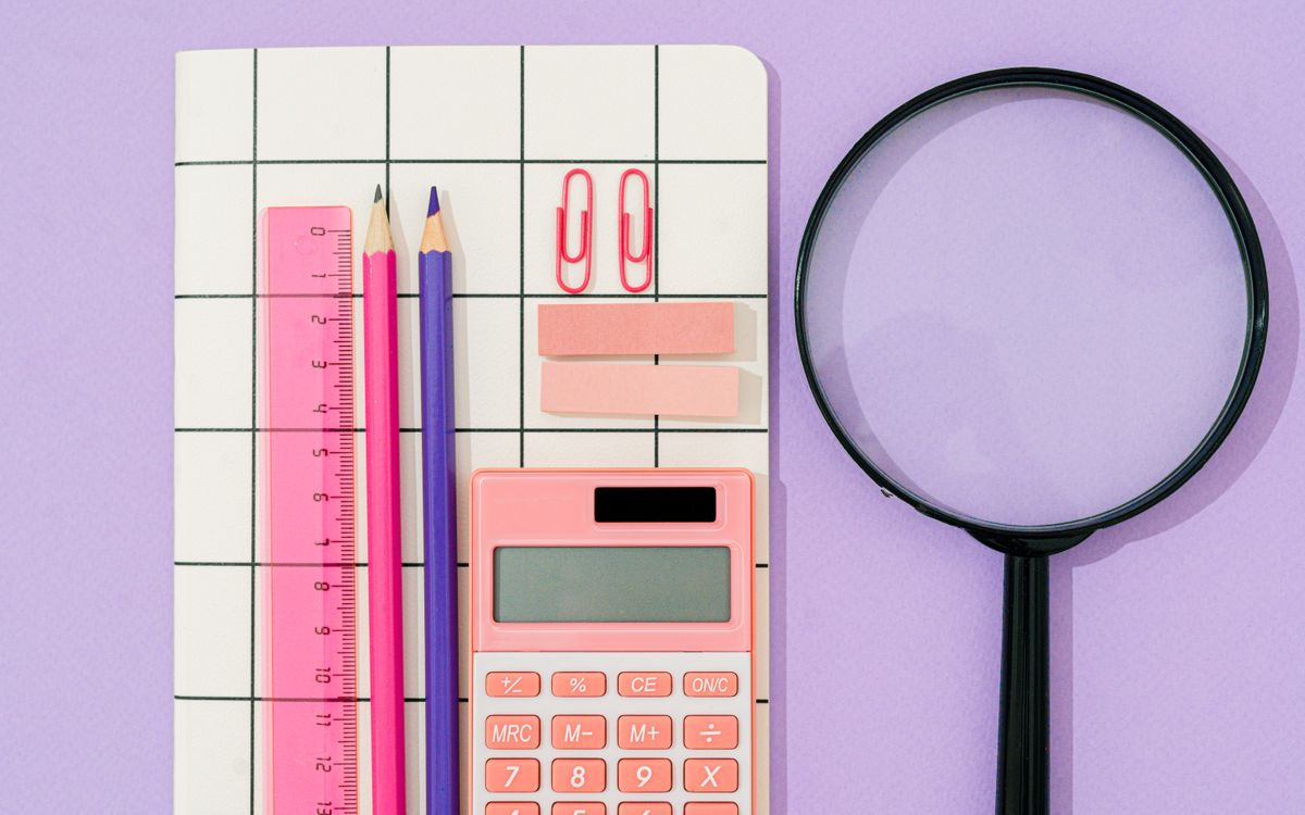 Flat lay of pastel office supplies on a grid notebook with purple background.