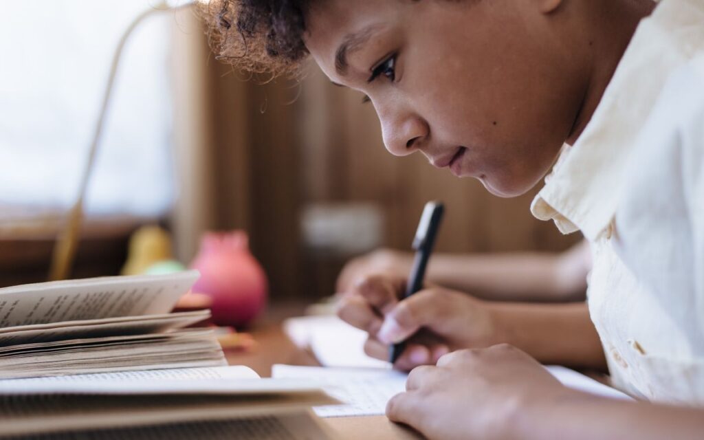 A young boy intensely writing indoors, capturing a moment of concentration.