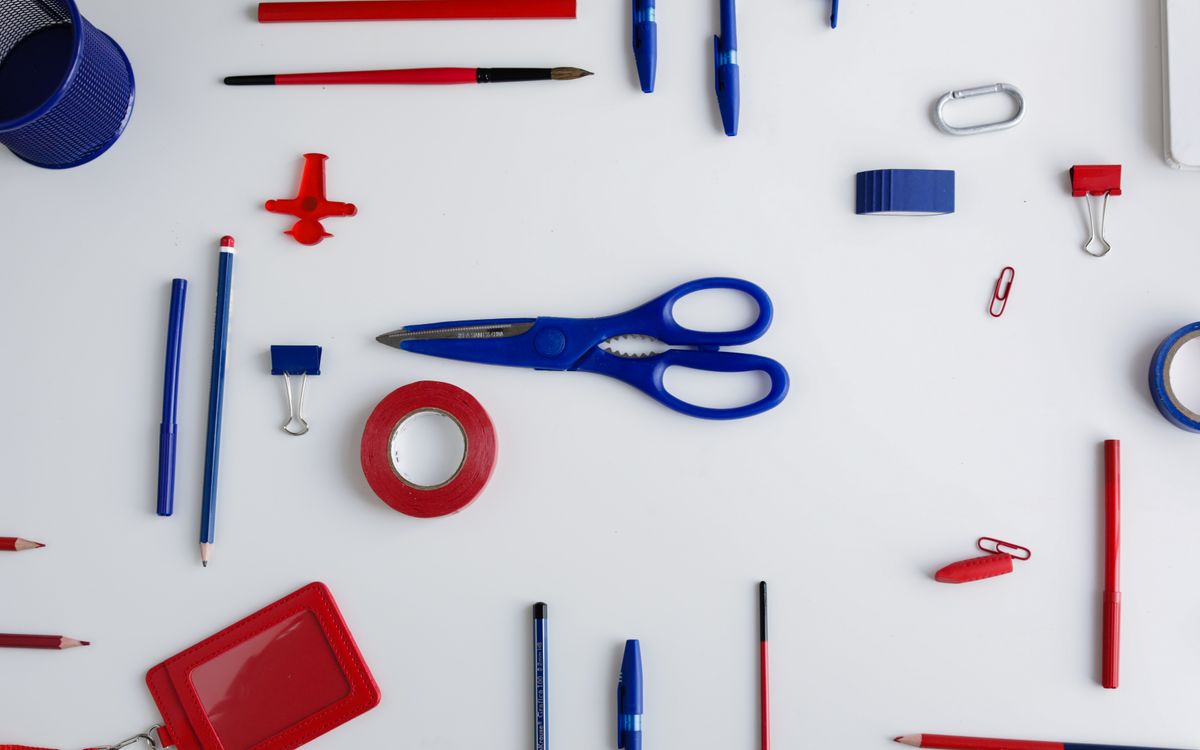 Top view of red and blue office stationery arranged on a white desk, ideal for creative projects.