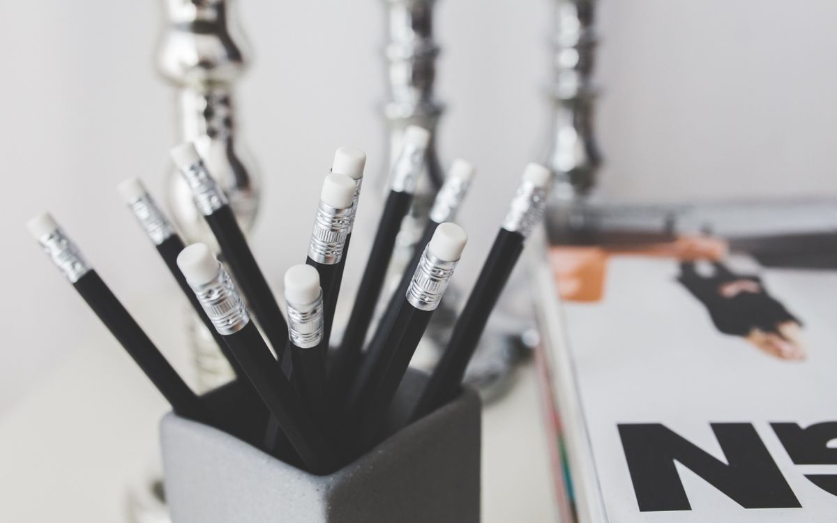 Black pencils with erasers in a holder on a minimalistic desk setup.