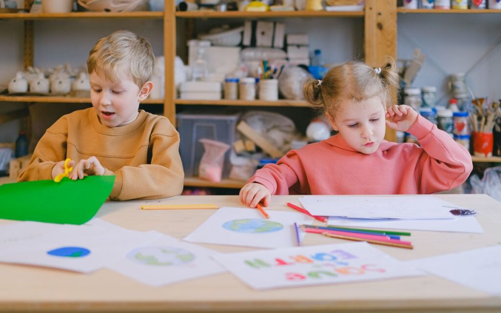 Two children engaged in arts and crafts in a classroom setting, focusing on creativity and learning.