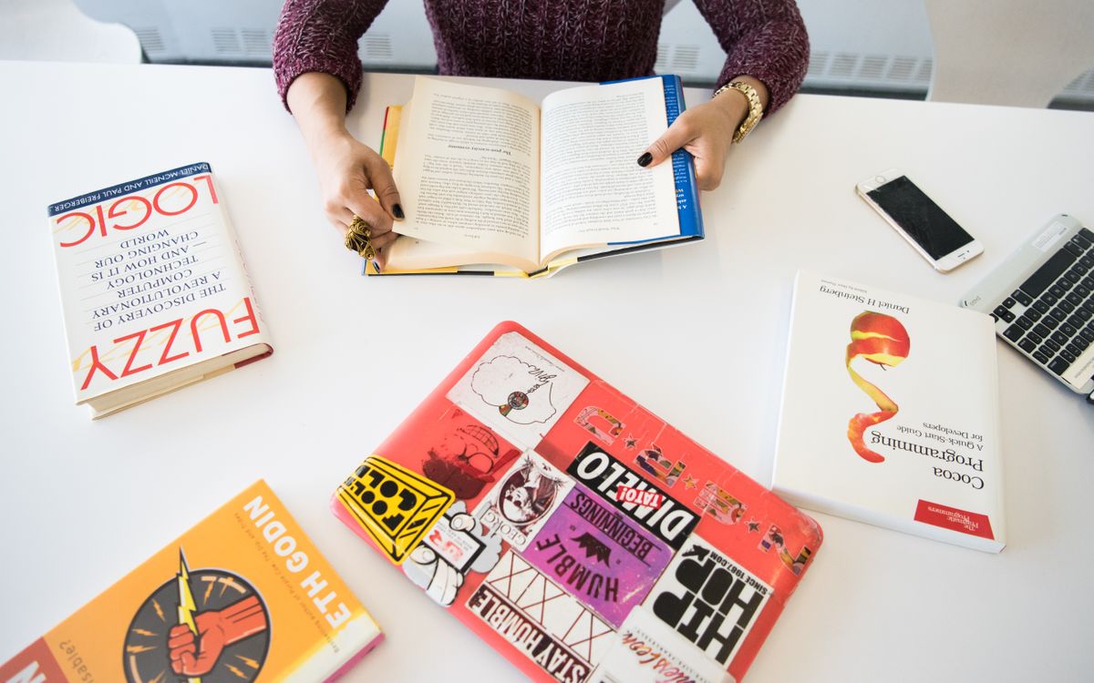 Overhead view of a workplace desk with books, a laptop, and technology essentials.