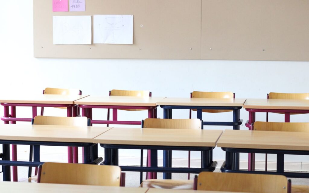 A bright, empty classroom in Einbeck, Deutschland, featuring wooden desks and chairs.