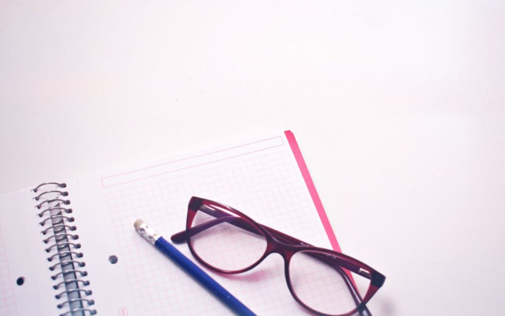 Eyeglasses resting on graph paper notebook with pencil, perfect for study or writing concepts.