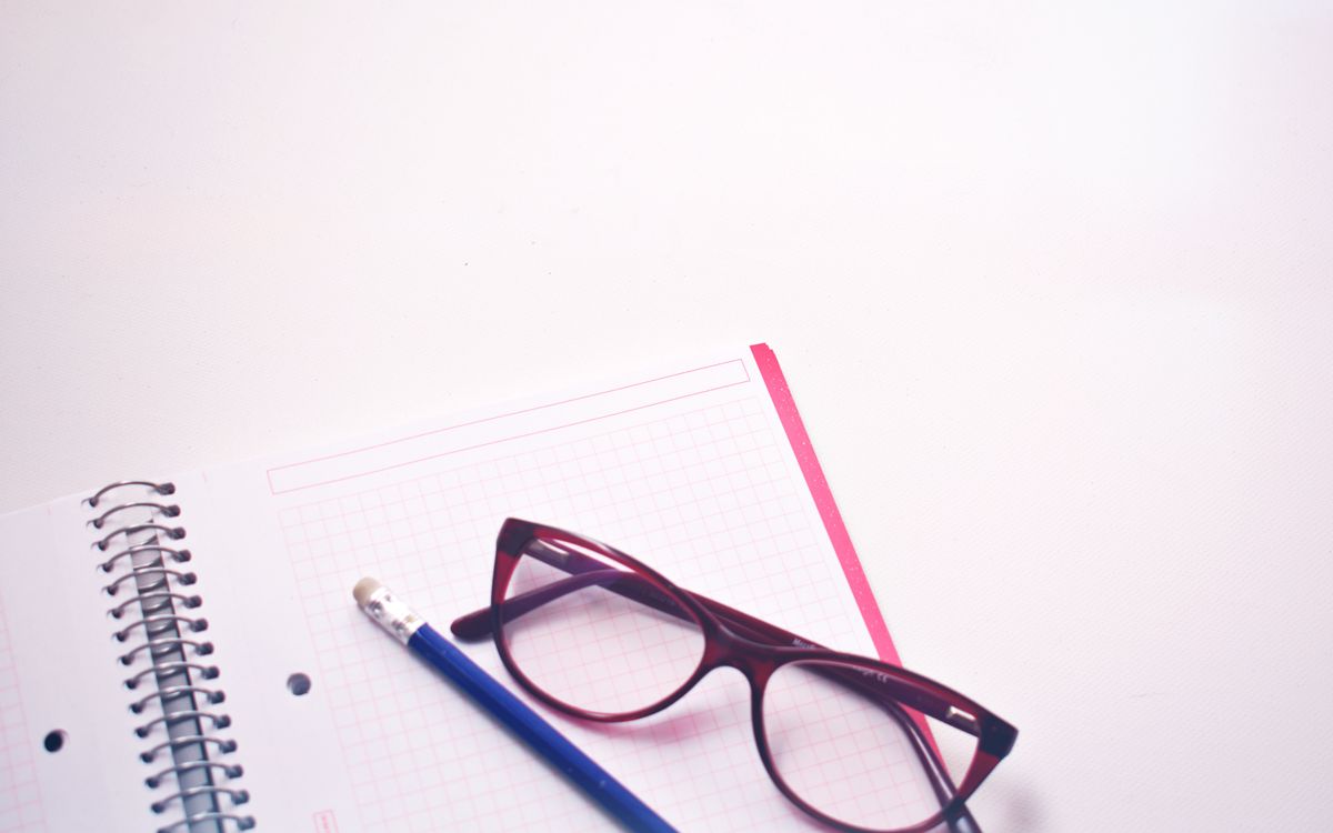 Eyeglasses resting on graph paper notebook with pencil, perfect for study or writing concepts.