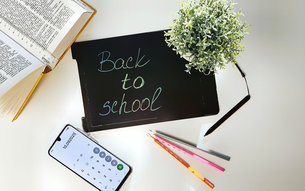 A bright, organized workspace for back to school featuring books, a phone, a plant, and stationery.