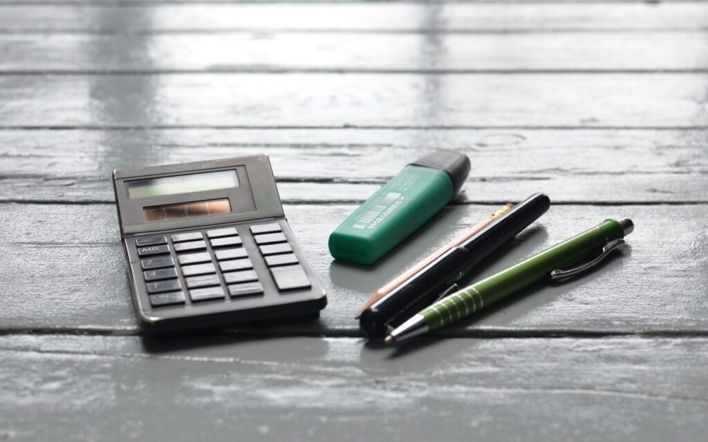 High angle of small electronic calculator green marker and pens on wooden table in office