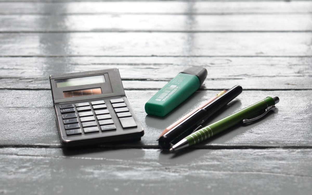 High angle of small electronic calculator green marker and pens on wooden table in office