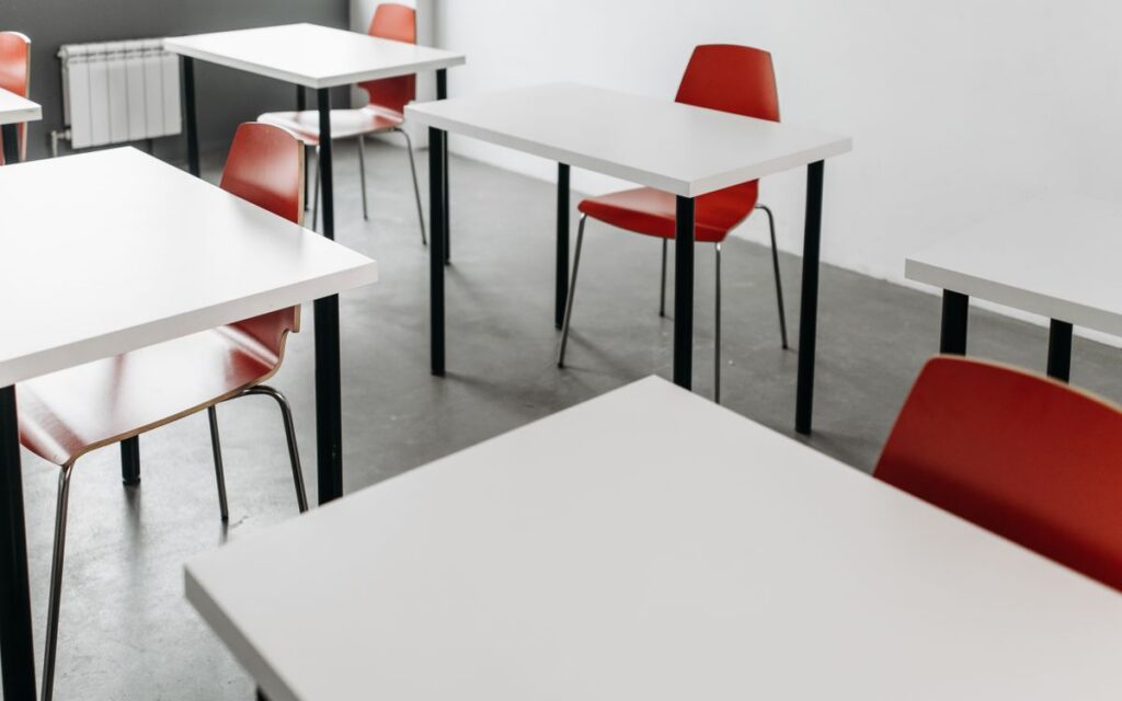 Minimalist classroom setup with red chairs and white desks, ideal for educational themes.